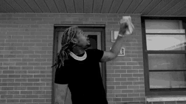 a man is standing in front of a brick building holding a bag of money .