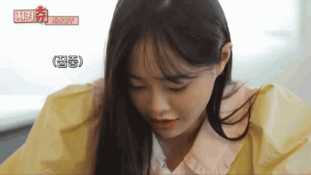 a woman in a yellow jacket with a pink collar looks down at something