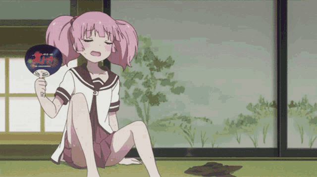 a girl with pink hair is sitting on the floor holding a fan that says ' i love you ' on it