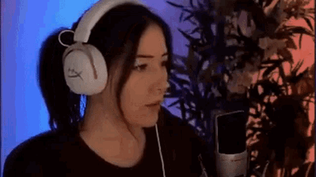 a woman wearing headphones is singing into a microphone in a recording studio .