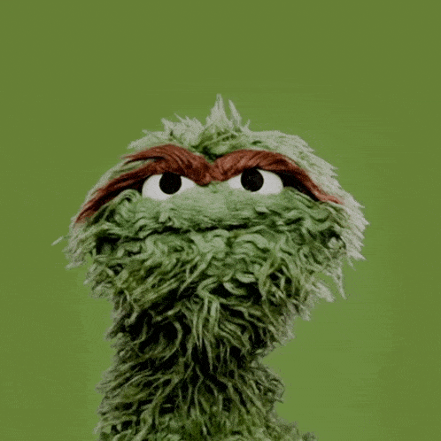 a green stuffed animal with a red g on the top
