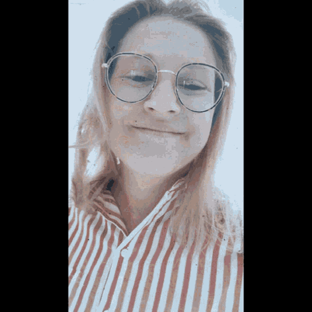 a woman wearing glasses and a striped shirt is smiling