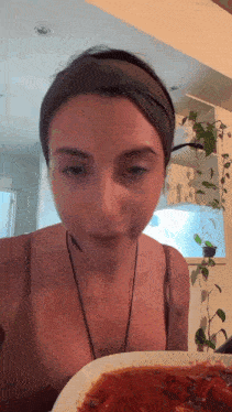 a woman wearing a headband and a necklace is eating a plate of food
