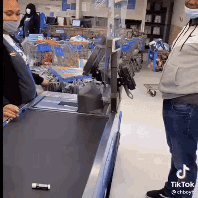 a woman wearing a mask is standing at a check out line in a store .