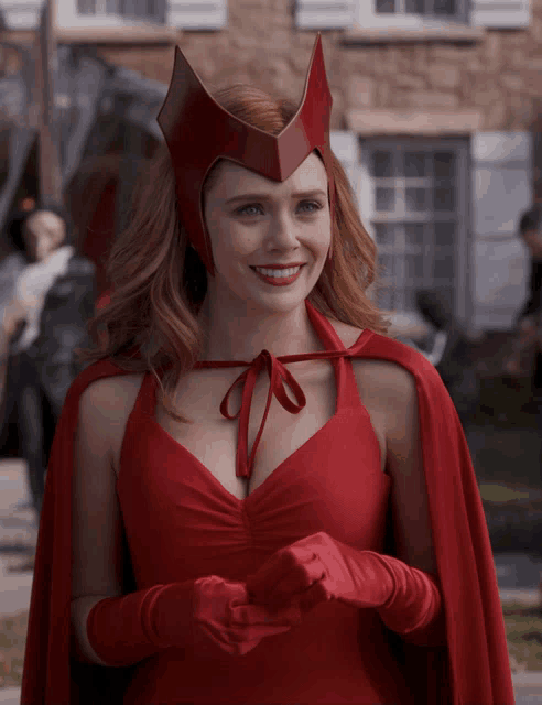 a woman wearing a red cape and gloves smiles for the camera