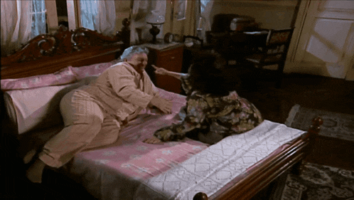 two women are laying on a bed and one of them is pointing