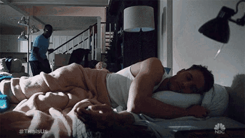 a man is sleeping in a bed with a blanket and a pillow .
