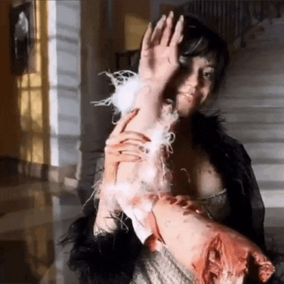 a woman in a fur coat is holding a bloody arm .