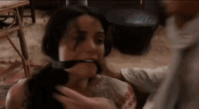 a man is holding a woman 's neck with a rope around her mouth .