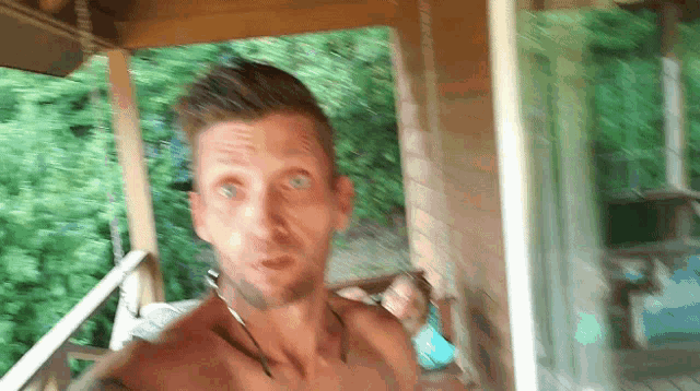 a man without a shirt is standing on a porch