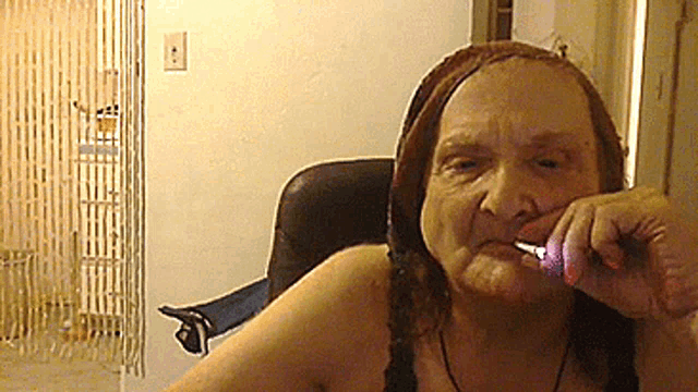 an elderly woman sitting in a chair with a cigarette in her mouth