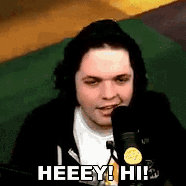 a young man is sitting in front of a microphone and making a funny face .