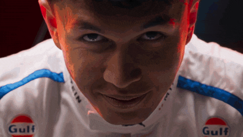 a close up of a person 's face with gulf logos on his shirt
