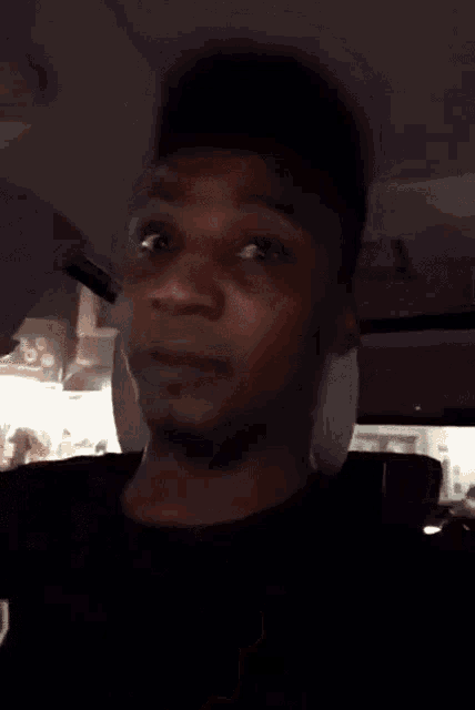 a man in a black shirt is making a funny face with his finger in his mouth