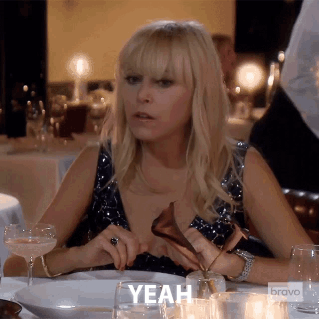 a woman is sitting at a table with a bravo logo on her shirt