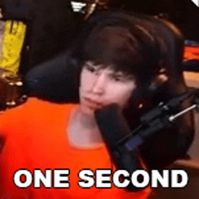 a man wearing headphones is sitting in front of a microphone with the words `` one second '' written on it .