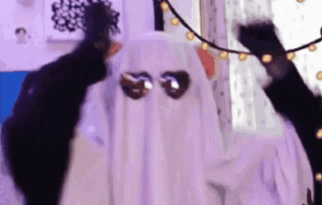 a person dressed as a ghost is dancing in a room with purple lights .