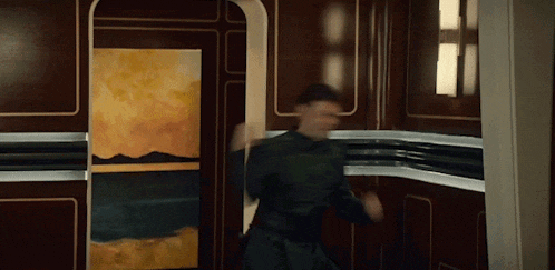a man is dancing in a room with a painting on the wall