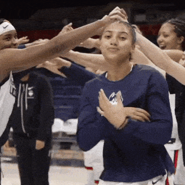 a group of female basketball players are huddled together and one of them is wearing a shirt that says nike