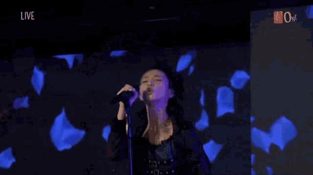 a woman is singing into a microphone in front of a blue screen .