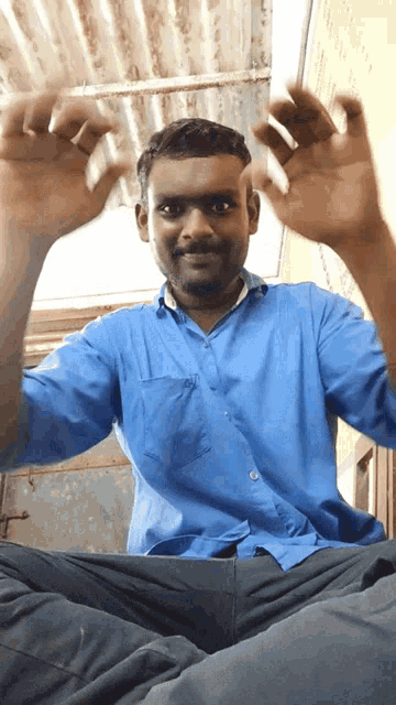 a man in a blue shirt is sitting down with his arms outstretched