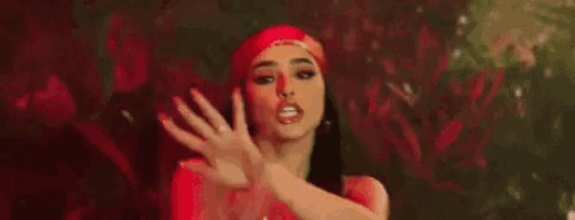 a woman is dancing in a club with her hands in the air and covering her face with her hands .