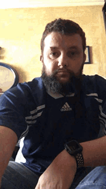 a man with a beard wears a blue adidas shirt