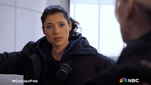 a woman with a walkie talkie on her shoulder is talking to a man in a chicago fire ad