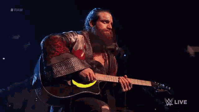 a man with a beard is playing a guitar on a stage in a dark room .