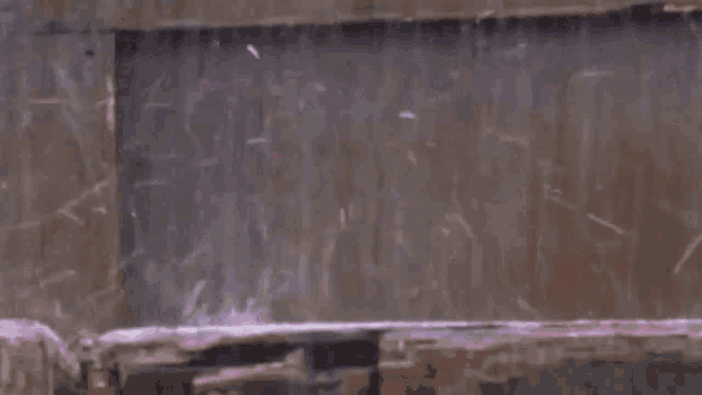 a pink robot is sitting on top of a pile of rocks in the rain .