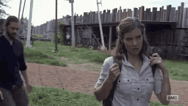 a man and a woman are walking down a dirt road .