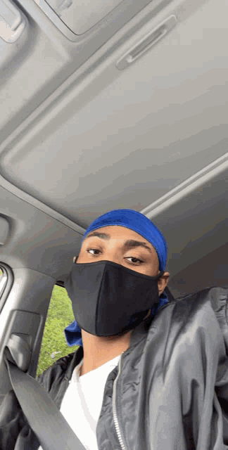 a man wearing a black mask and a blue headband is in a car