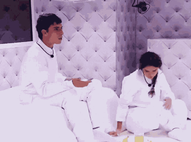 a man and a woman are sitting on a bed in white clothes