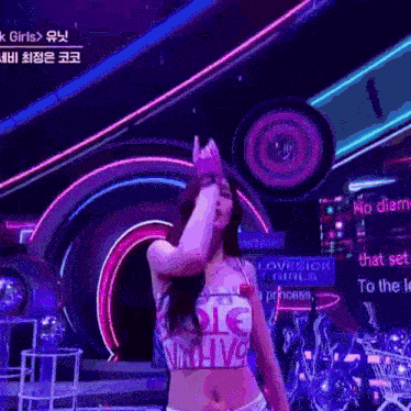a woman in a crop top and shorts is dancing on a stage with neon lights .