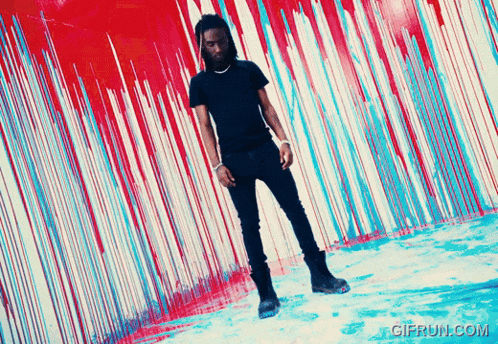 a man in a black shirt is standing in front of a painting that says giffun.com on the bottom