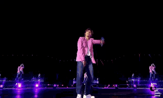 a man is standing on a stage with his arms outstretched and holding a microphone .