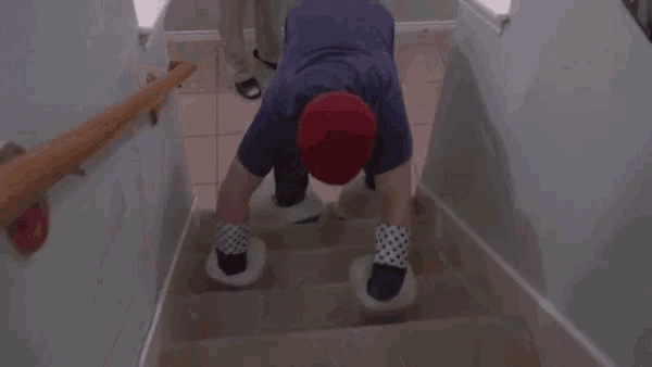 a man wearing a red hat and polka dot socks crawls down stairs