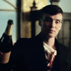 a man in a suit is holding a bottle of champagne in his hand