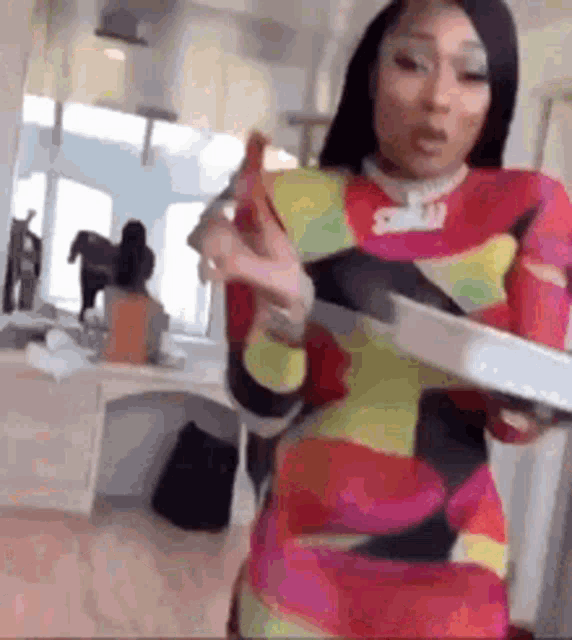 a woman in a colorful dress is holding a tray and a knife .