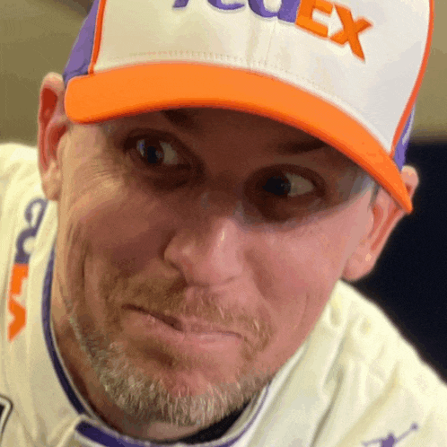 a man wearing a fedex hat makes a face