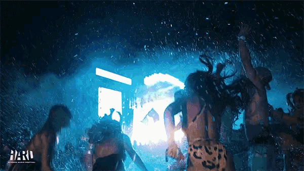 a group of people are dancing in the rain with the word hard on the bottom right