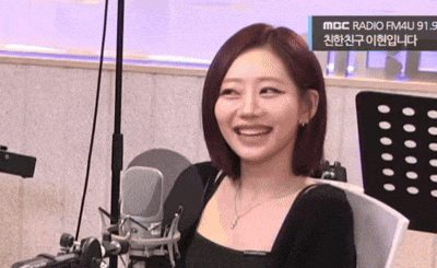 a woman is smiling while sitting in front of a microphone and a sign that says mbc radio fm4u 91.9