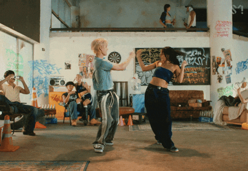 a group of people are dancing in a room with graffiti on the walls and a sign that says ' a ' on it