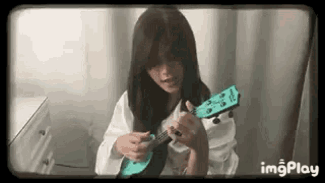 a young woman is playing a blue ukulele in a room .