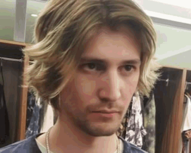 a man with long blonde hair and a beard is making a funny face in a locker room .