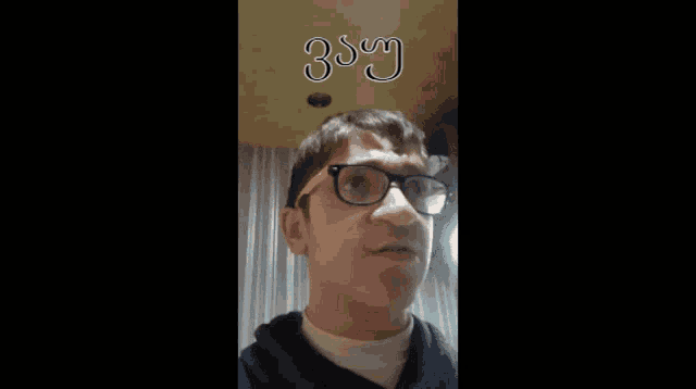 a man wearing glasses is making a funny face with the word say written on the ceiling above him