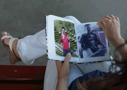 a woman is looking at a photo album with a man in a red shirt