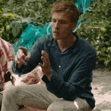 a man in a blue shirt is sitting on a beach