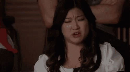a woman is making a funny face while sitting in a chair with her arms crossed .