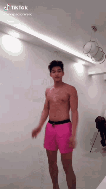 a shirtless man wearing pink shorts is dancing in a room .